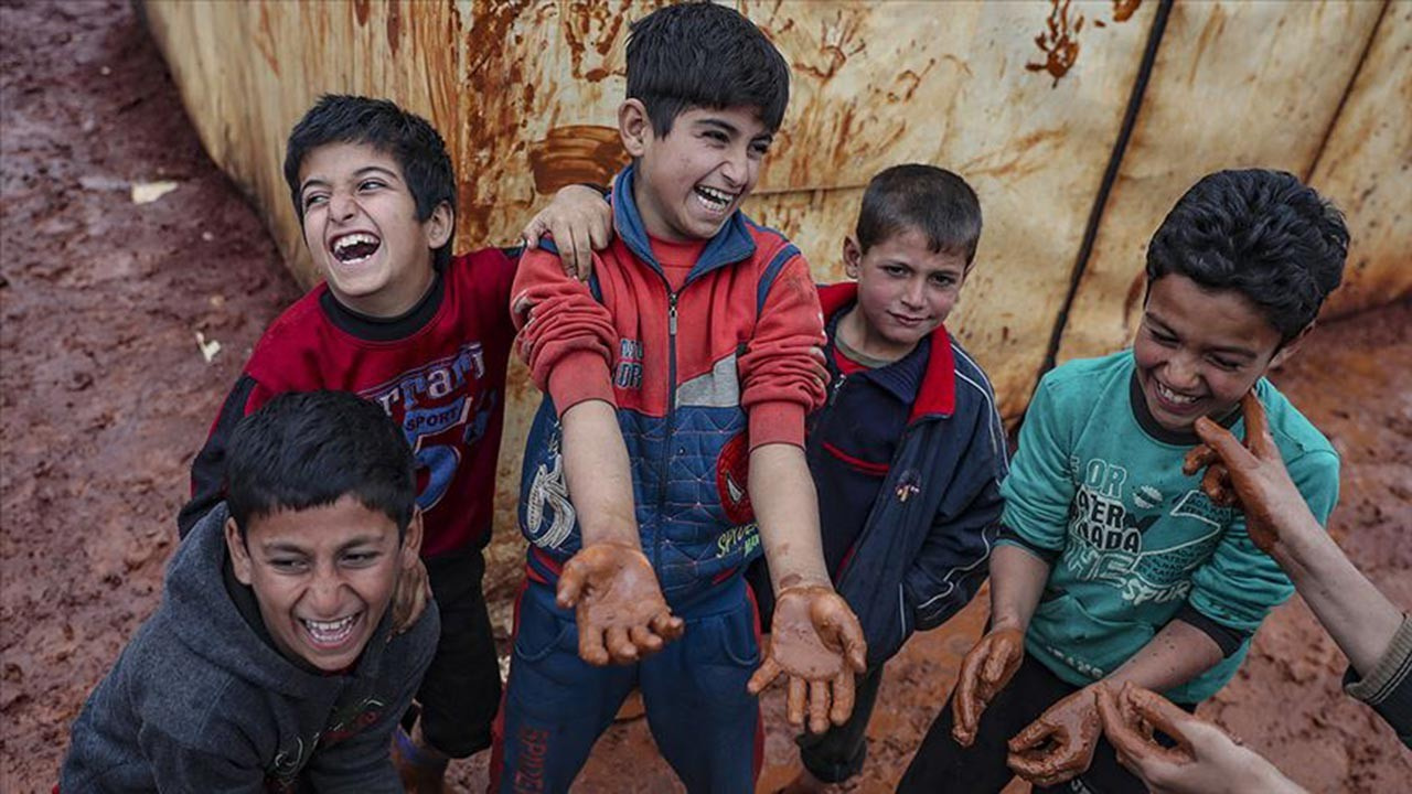 Çamura batmış kampta kalan çocukların gülüşleri